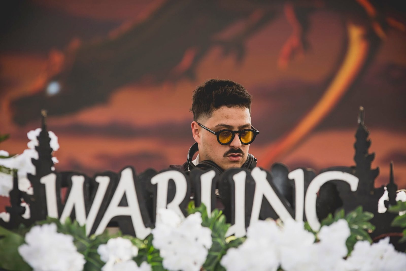 Kevin Disko atrás do letreiro WARUNG ao entardecer